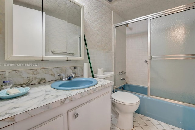 full bathroom featuring tile patterned flooring, a textured ceiling, toilet, shower / bath combination with glass door, and vanity