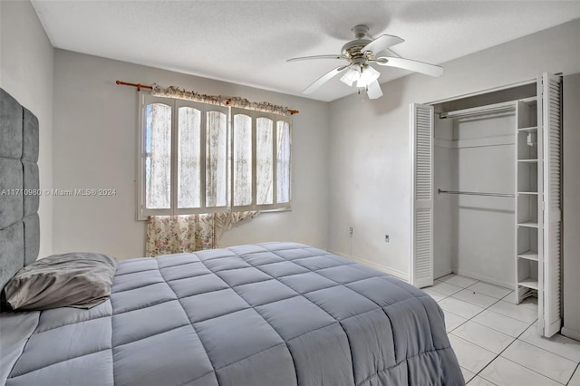 tiled bedroom with ceiling fan, a closet, and a textured ceiling