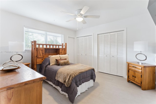 bedroom featuring multiple closets, light hardwood / wood-style floors, and ceiling fan