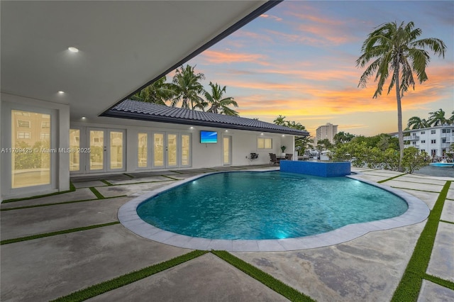 pool at dusk with a patio area