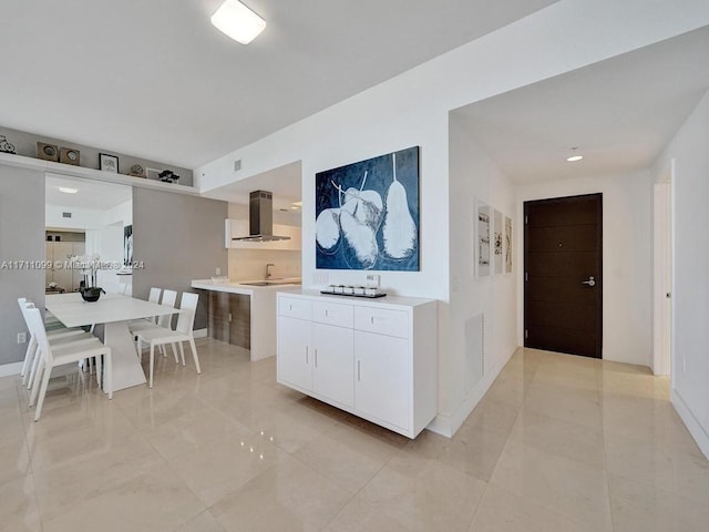 kitchen featuring sink, white cabinetry, and wall chimney range hood