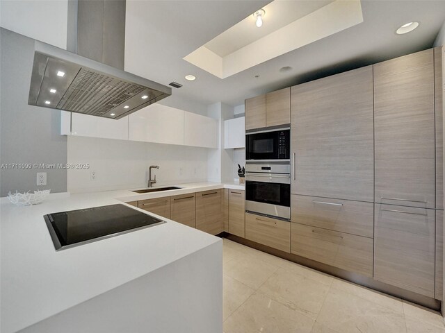 kitchen with island exhaust hood, light tile patterned floors, white cabinetry, and black appliances