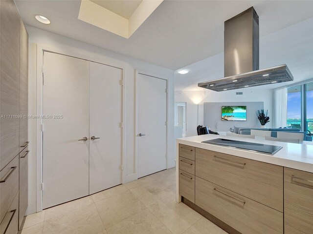 17301 Biscayne Blvd Unit 2008, North Miami Beach, FL 33160 - kitchen with light countertops, island exhaust hood, black electric stovetop, light tile patterned flooring, and light brown cabinets