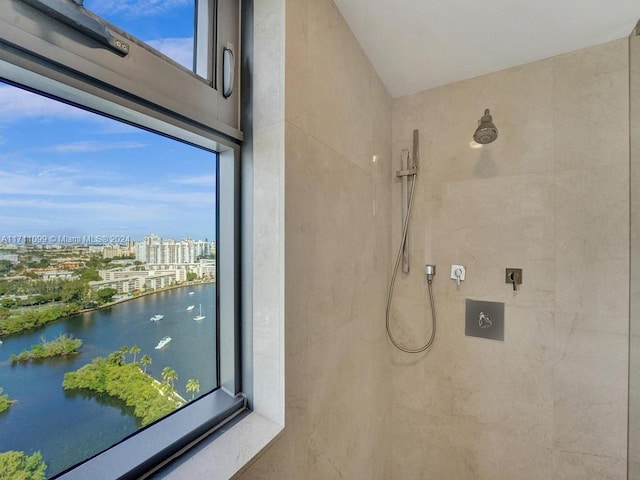 bathroom featuring a tile shower and a water view