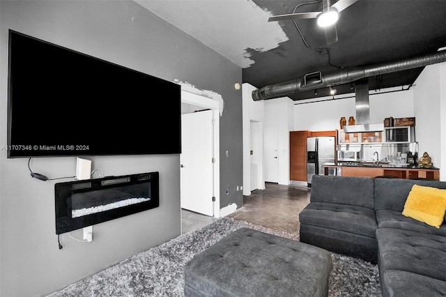 living room with ceiling fan, concrete flooring, and a high ceiling