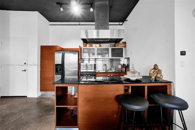 kitchen featuring a breakfast bar, track lighting, ventilation hood, sink, and stainless steel appliances