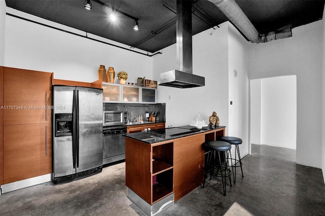 kitchen featuring a high ceiling, kitchen peninsula, a kitchen bar, exhaust hood, and appliances with stainless steel finishes