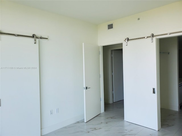 unfurnished bedroom with a barn door, a spacious closet, and a closet