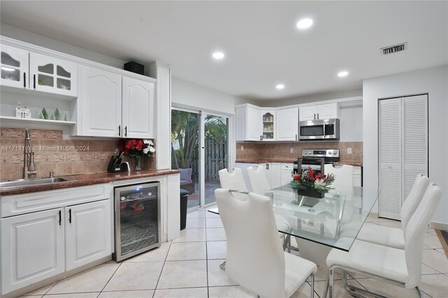 kitchen featuring sink, appliances with stainless steel finishes, tasteful backsplash, white cabinetry, and beverage cooler