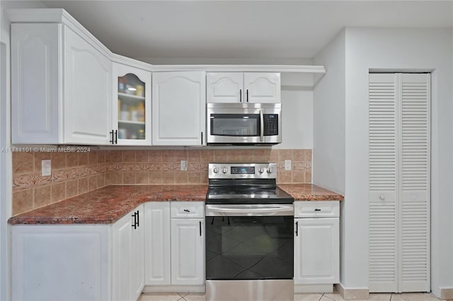 kitchen featuring dark stone countertops, light tile patterned flooring, white cabinets, and stainless steel appliances