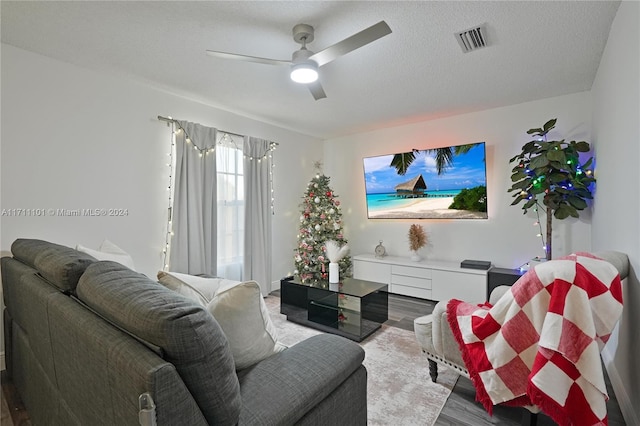 living room with ceiling fan, wood-type flooring, and a textured ceiling