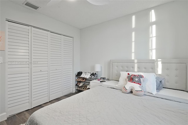 bedroom featuring a textured ceiling, ceiling fan, a closet, and dark hardwood / wood-style floors