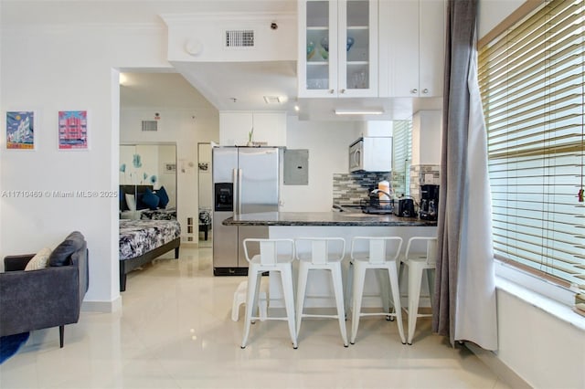 kitchen with backsplash, electric panel, white cabinets, stainless steel refrigerator with ice dispenser, and kitchen peninsula