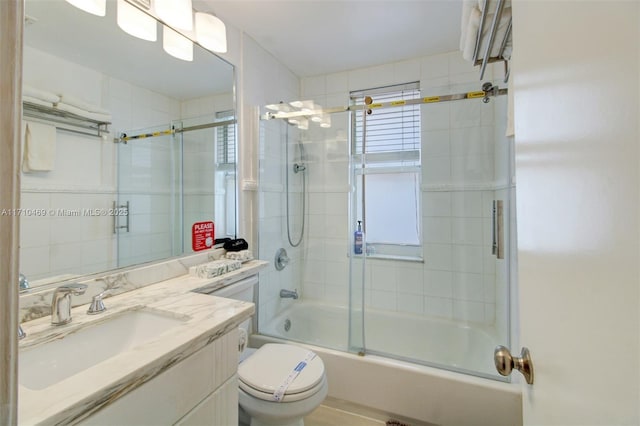 full bathroom featuring vanity, toilet, and shower / bath combination with glass door