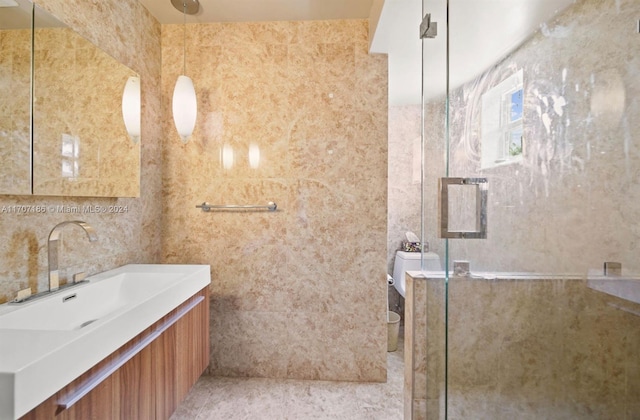 bathroom with vanity, an enclosed shower, and tile walls