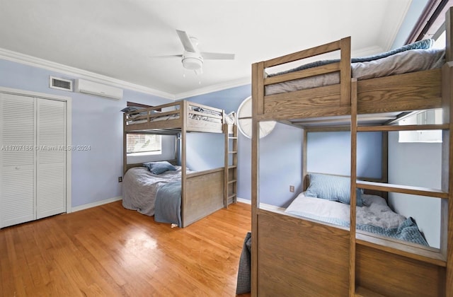 bedroom featuring ceiling fan, wood-type flooring, ornamental molding, and a closet