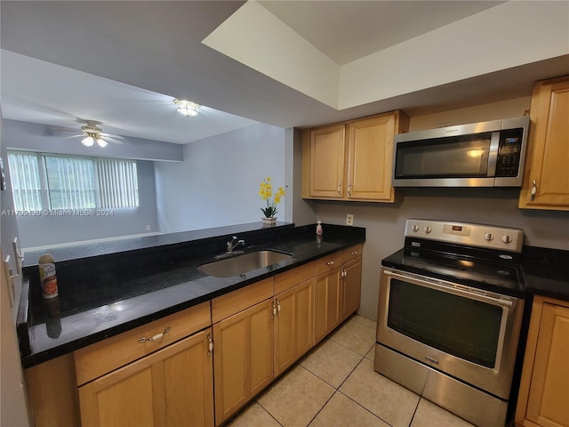 kitchen with dark stone counters, sink, ceiling fan, light tile patterned flooring, and stainless steel appliances