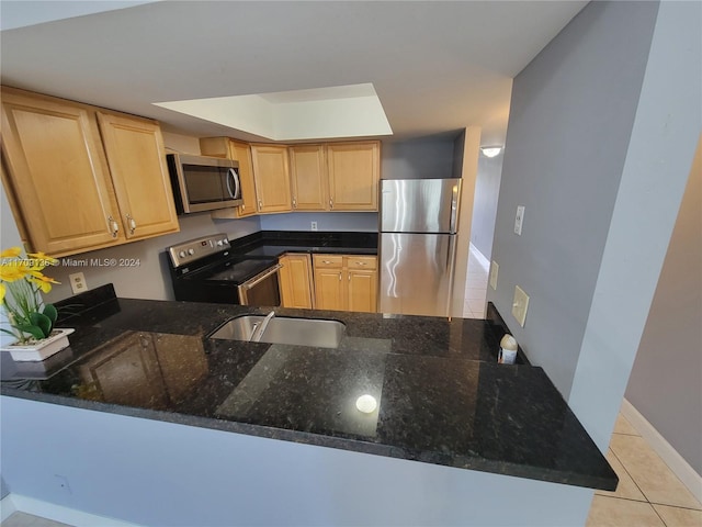 kitchen with kitchen peninsula, stainless steel appliances, sink, light tile patterned floors, and dark stone countertops