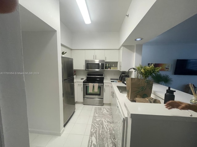 kitchen with white cabinetry, stainless steel appliances, backsplash, kitchen peninsula, and light tile patterned floors