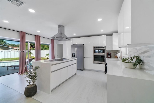 kitchen with decorative backsplash, appliances with stainless steel finishes, island range hood, sink, and white cabinetry