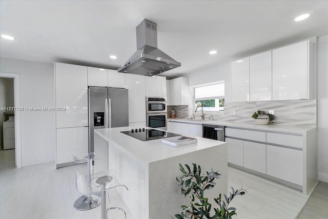 kitchen with backsplash, island range hood, stainless steel appliances, a kitchen island, and white cabinetry