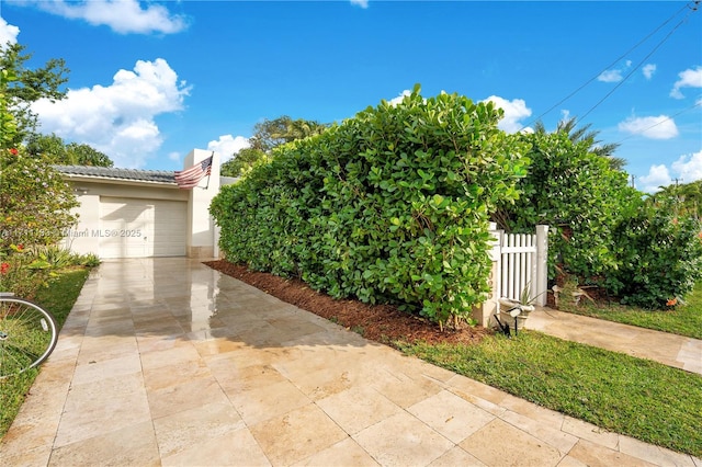 view of front of property featuring a tile roof, stucco siding, fence, a garage, and driveway