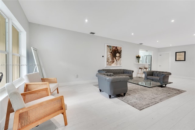 living room with baseboards, light wood finished floors, visible vents, and recessed lighting