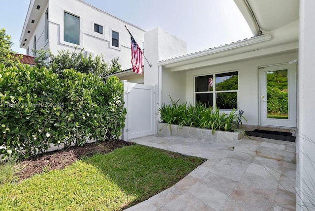 exterior space with a lawn, a patio area, a gate, and stucco siding