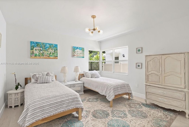 bedroom featuring light wood-type flooring, a notable chandelier, and baseboards