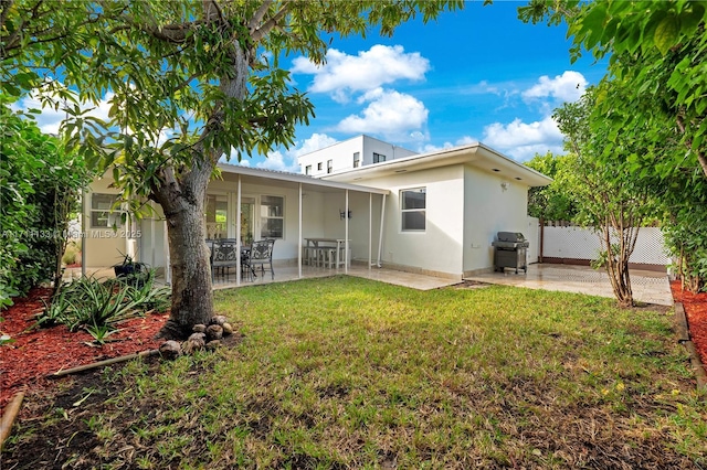 rear view of house featuring stucco siding, fence, a lawn, and a patio