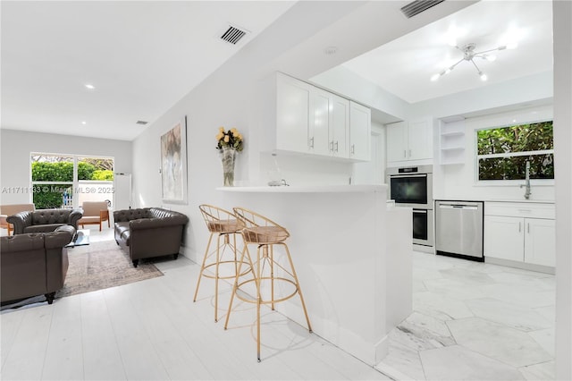 kitchen with white cabinetry, visible vents, appliances with stainless steel finishes, and open floor plan