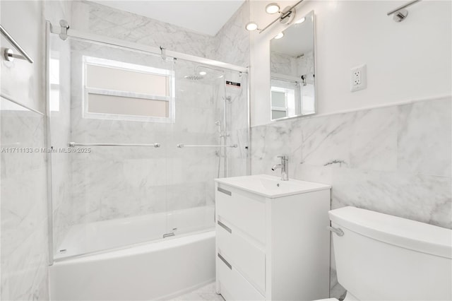 full bath featuring marble finish floor, tile walls, bath / shower combo with glass door, toilet, and vanity