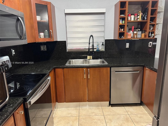 kitchen with backsplash, sink, dark stone countertops, light tile patterned floors, and appliances with stainless steel finishes