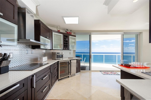 kitchen featuring black electric stovetop, a water view, wine cooler, wall chimney exhaust hood, and decorative backsplash