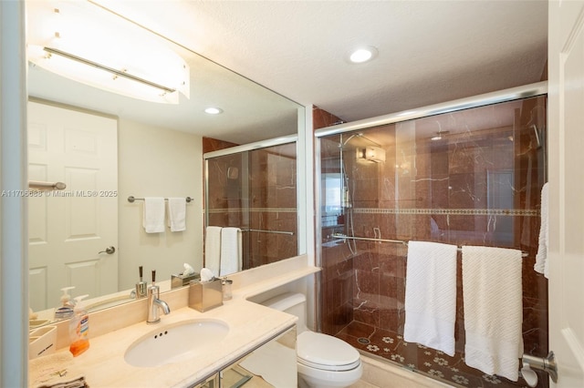 bathroom featuring toilet, a shower with shower door, and sink