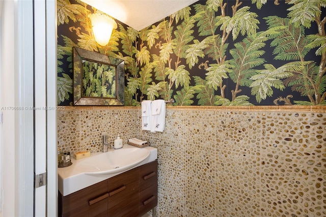 18671 Collins Ave Unit 3101, Sunny Isles Beach, FL 33160 - bathroom featuring wallpapered walls, vanity, wainscoting, and tile walls