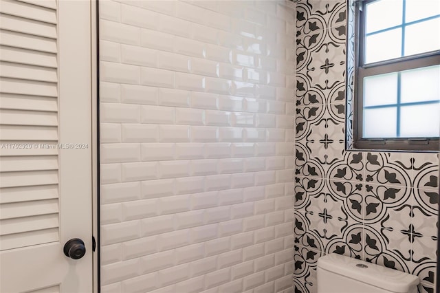 bathroom featuring tiled shower and toilet