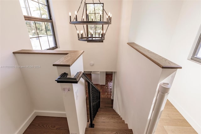 stairs featuring hardwood / wood-style floors and an inviting chandelier