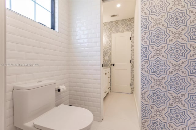 bathroom featuring tile patterned flooring, toilet, and tile walls