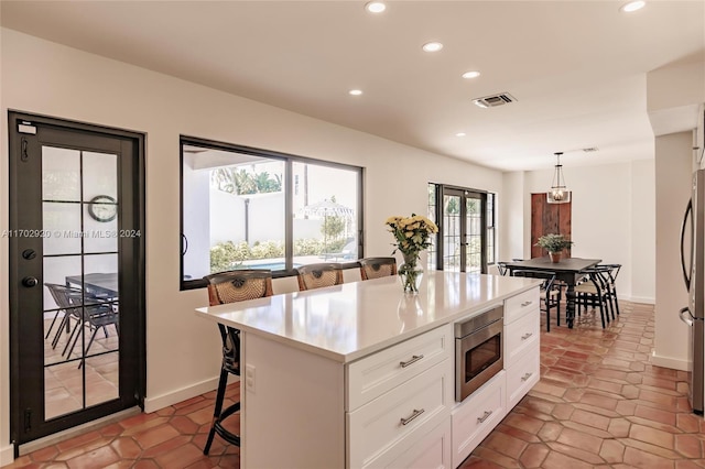 kitchen featuring white cabinets, appliances with stainless steel finishes, a center island, and plenty of natural light