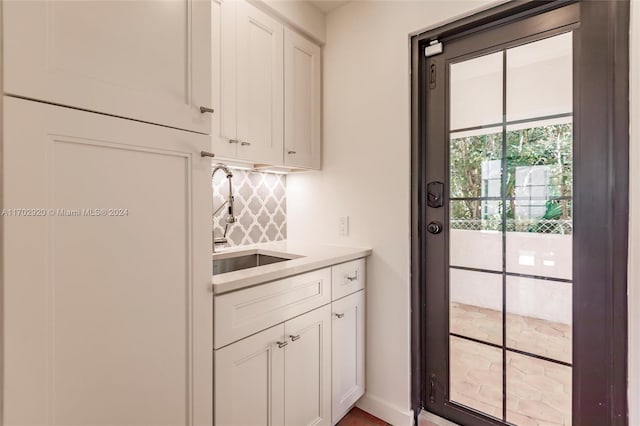 kitchen featuring decorative backsplash, white cabinets, and sink