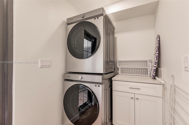 washroom with cabinets and stacked washing maching and dryer