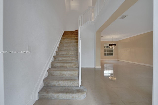 staircase featuring an inviting chandelier, tile patterned floors, visible vents, and baseboards