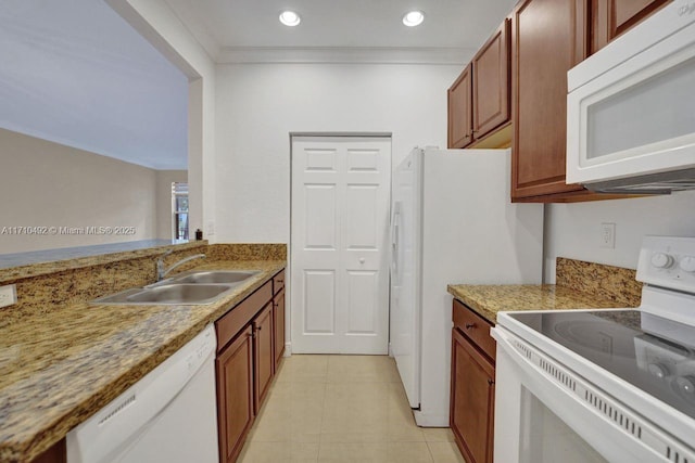 kitchen with a sink, white appliances, brown cabinets, crown molding, and light tile patterned floors