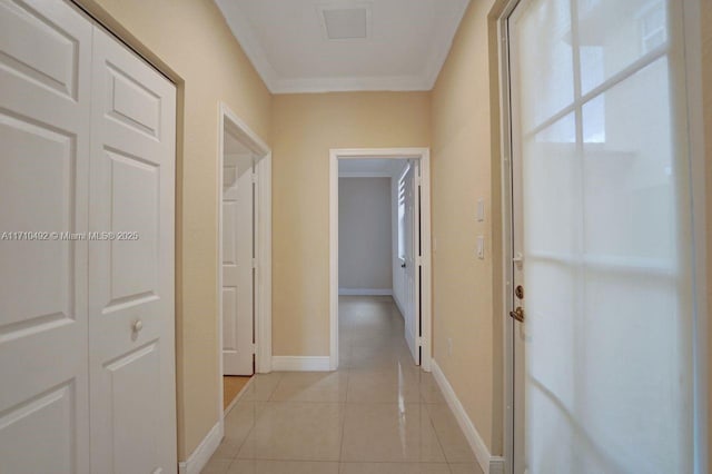 corridor featuring baseboards, crown molding, visible vents, and light tile patterned floors