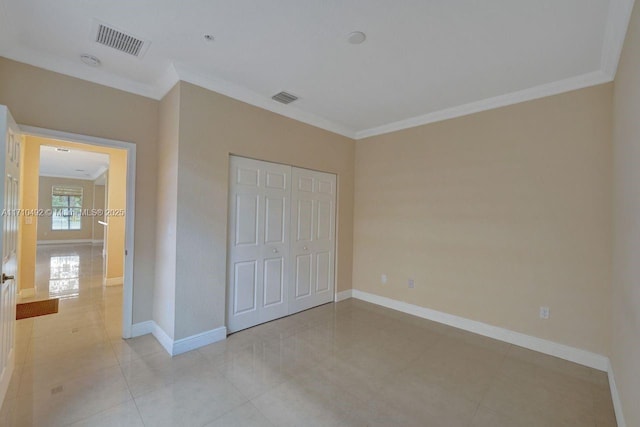 unfurnished bedroom with a closet, visible vents, baseboards, and ornamental molding