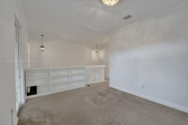 carpeted spare room featuring attic access, baseboards, visible vents, and ornamental molding