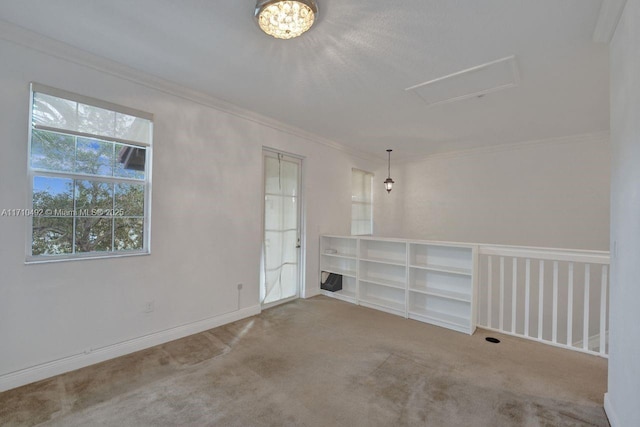 spare room with attic access, baseboards, carpet floors, and ornamental molding