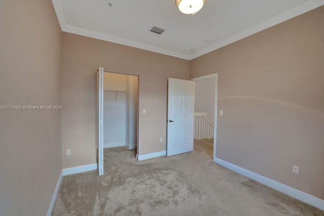 unfurnished bedroom with a spacious closet, a closet, light colored carpet, and ornamental molding