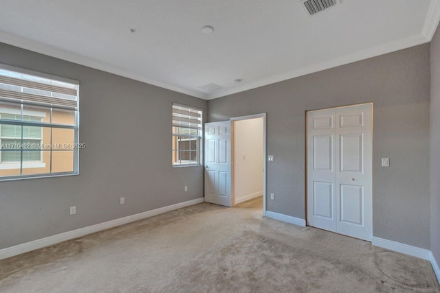 unfurnished bedroom featuring carpet floors, visible vents, ornamental molding, and multiple windows
